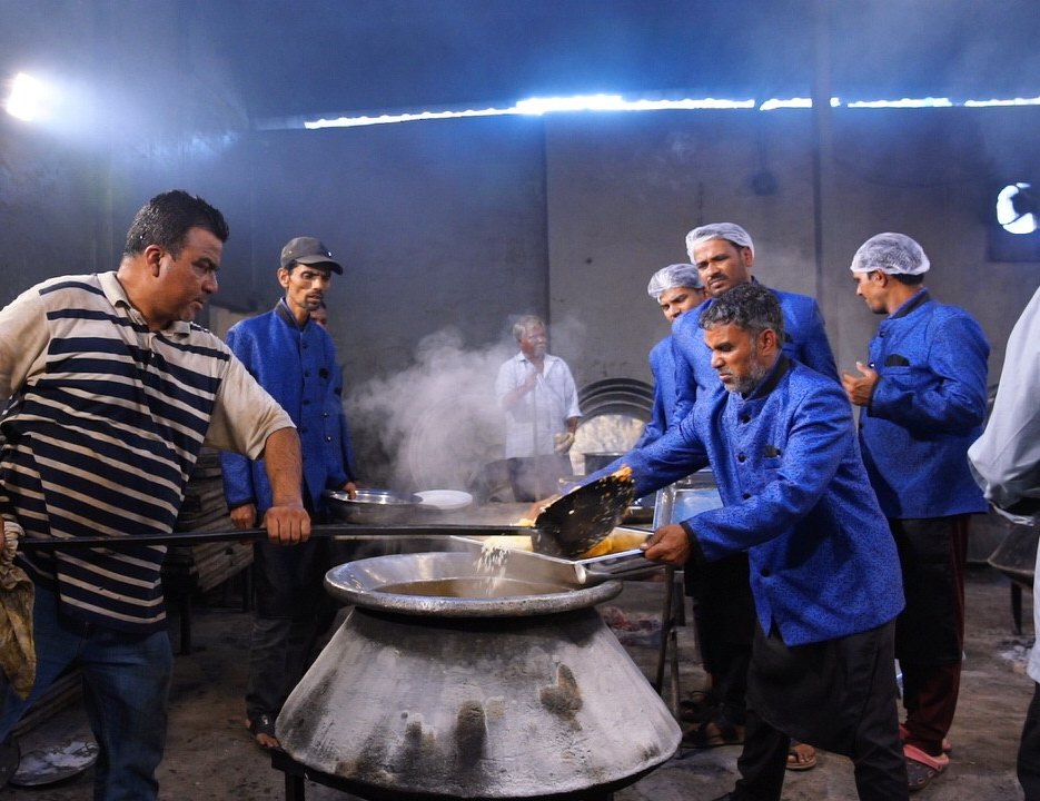 Zarafé chef team in blue uniforms cooking dum biryani in a large deg for the expo dinner, 2025